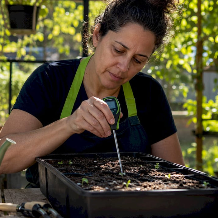 Woman inserting soil thermometer into seed tray